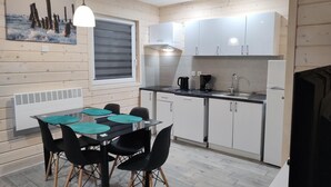 Cocina compacta con zona de comedor, que incluye una mesa con sillas, cafetera y refrigerador.