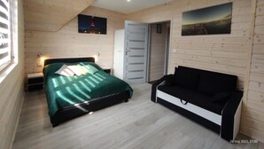 Un dormitorio con cama, mesita de noche, cómoda, banco y dos cuadros en la pared.
