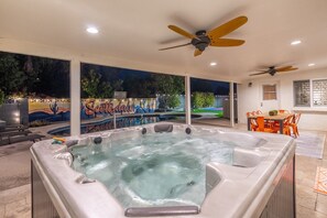 Ein Whirlpoolbereich mit Wandgemälde, Deckenventilatoren und einem Patio-Tisch.