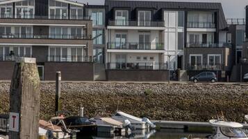 Un puerto deportivo con barcos amarrados, un muro de piedra y edificios modernos de varios pisos al fondo.