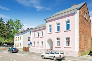 A pink building with a brick section, a parking sign, and a blue car. - Modern Apartment With Terrace (Bad Camberg)