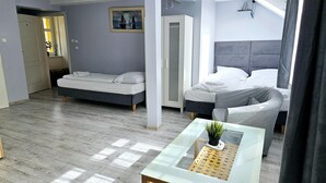 A modern bedroom with two beds, a glass coffee table, and a painting on the wall.