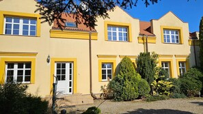 A yellow building with multiple windows and a door, surrounded by greenery and a gravel path. - Comfortable House With Private Pool, Kolczewo (gmina Wolin)