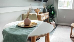 A dining area with a round table, a vase with dried plants, and a television mounted on the wall. - Sanctuary Co Loft in Downtown Johnson City (Johnson City)