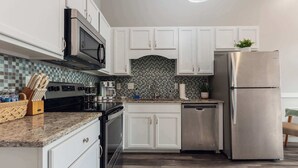 A modern kitchen with white cabinets, a stainless steel refrigerator, and a tiled backsplash. - Sanctuary Co Loft in Downtown Johnson City (Johnson City)