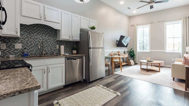 A modern kitchen with white cabinets, a stainless steel refrigerator, and a tiled backsplash. - Sanctuary Co Loft in Downtown Johnson City (Johnson City)
