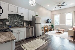 A modern kitchen with white cabinets, a stainless steel refrigerator, and a tiled backsplash.