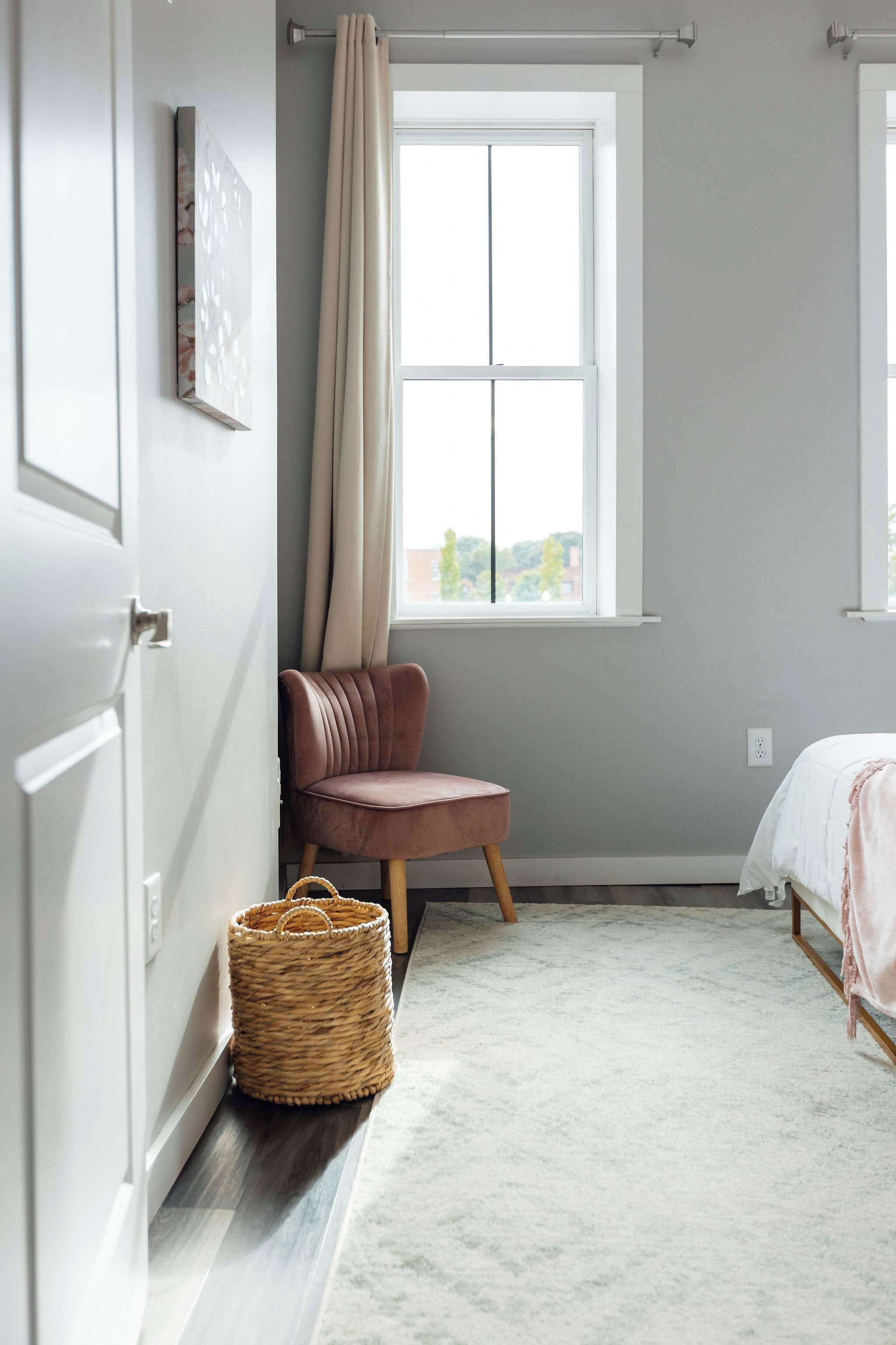 A bedroom with a bed, a chair, a window, and a door.