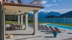 A poolside area with a view of mountains and a lake.