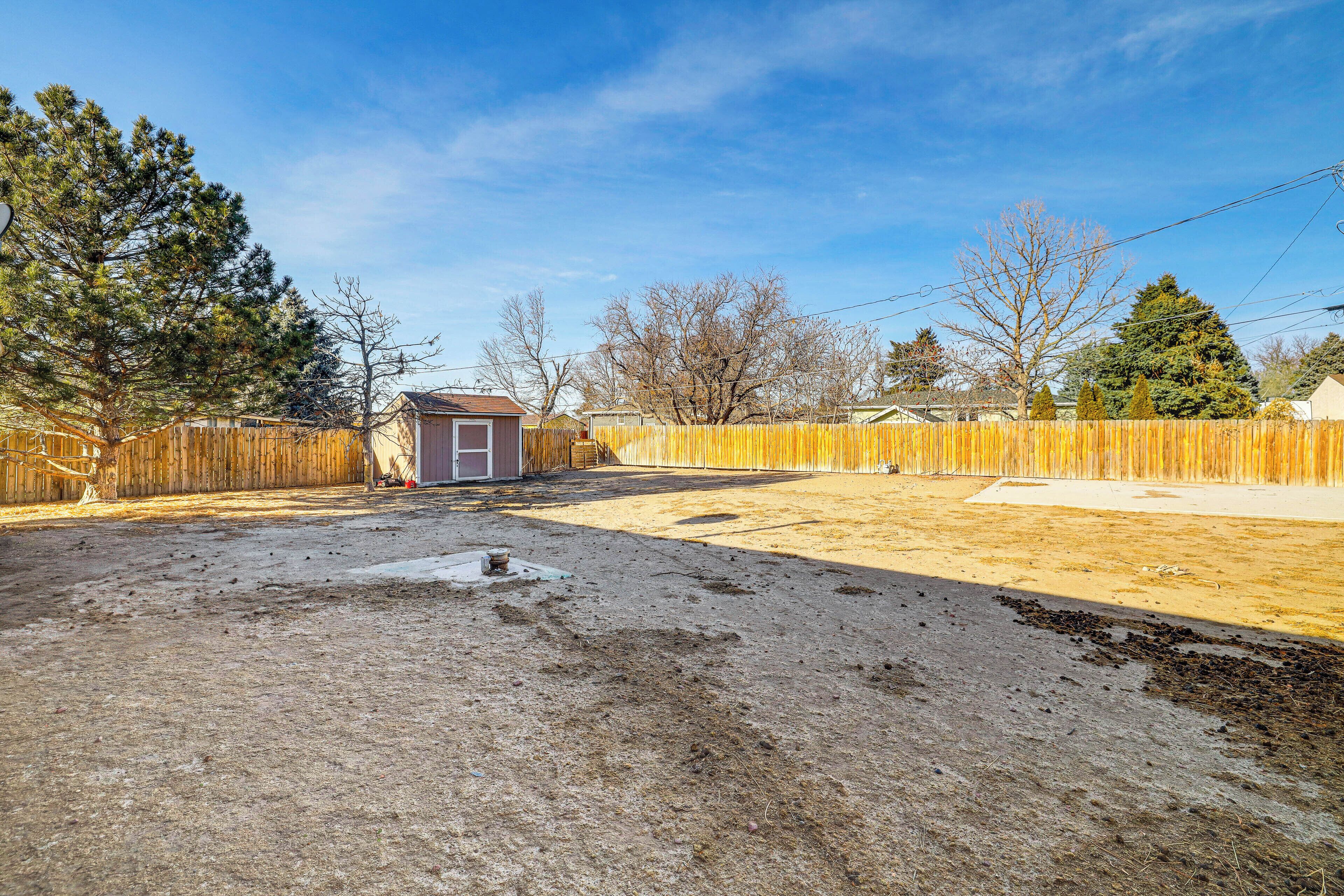 A backyard with a wooden fence, a shed, and a small garden area.