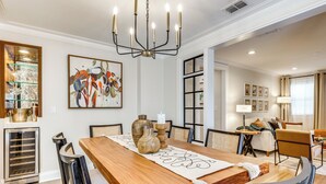 A dining area with a wooden table, chairs, a chandelier, and a large abstract painting on the wall. - Fenced Yard: Lakeland Home Adjacent to Golf Course (Lakeland)