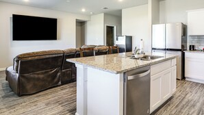 A modern kitchen with a central island, white cabinetry, and a stainless steel refrigerator. - 13 Mi to Baton Rouge: Family-Friendly Home (Zachary)