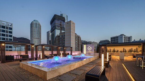 A rooftop bar with a pool, seating areas, and city views. - Urban Groove Hotel (Busan)
