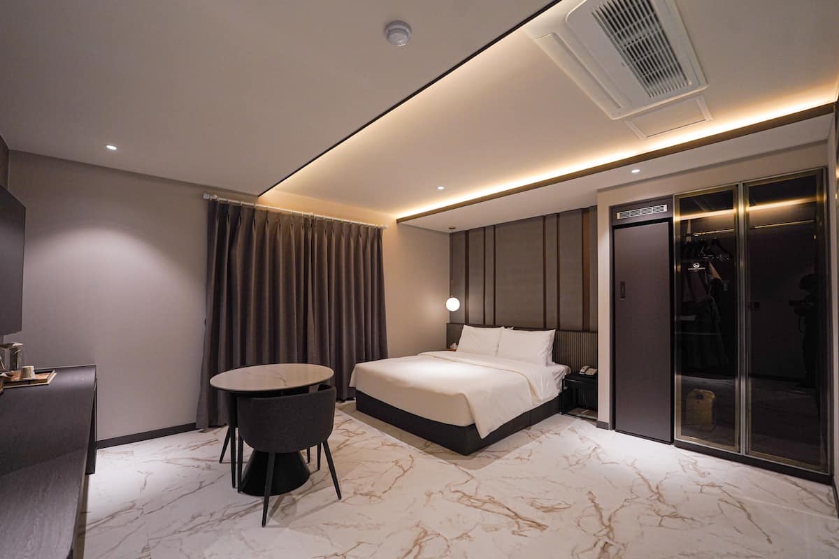 A modern hotel room with a bed, a desk, and a chair.