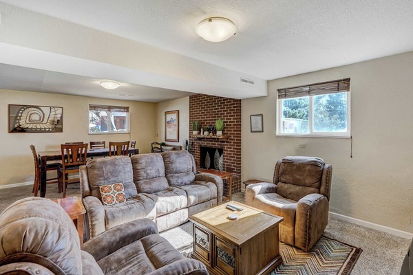 Spacious lower-level living area! Relax by the brick fireplace, enjoy cozy seating, and gather with family in this inviting space..