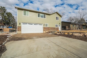 A two-story house with a garage, a stone foundation, and a landscaped driveway.