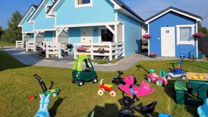 A two-story blue house with a porch, a garage, and a small garden area with children's toys. - Comfortable Holiday Homes for 6 People, Niechorze (Rewal)