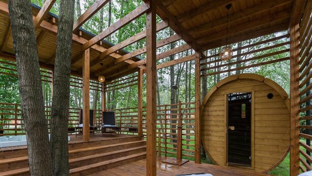 Eine Holzterrasse mit Liegestühlen und einer überdachten Sitzgruppe.