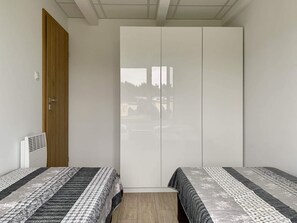 Ein Schlafzimmer mit zwei Einzelbetten, einem Kleiderschrank und einer Heizung.
