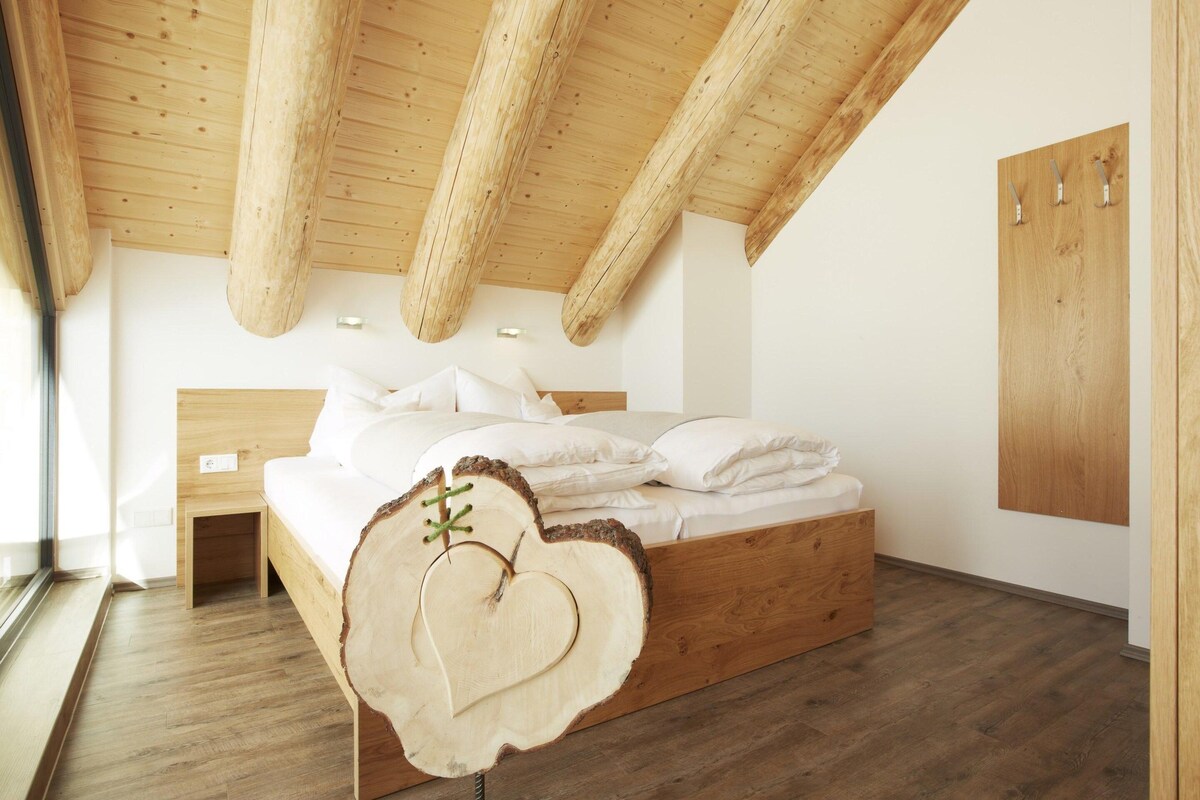 A bedroom with a wooden bed, a heart-shaped headboard, and a wooden ceiling.
