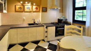 A kitchen with a black and white checkered floor, a stove, a sink, and a chair. - Holiday Home, Oasis of Peace, Polanow (gmina Polanów)