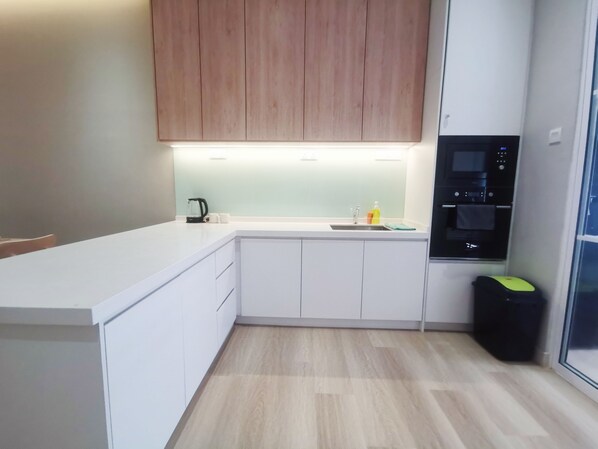 A modern kitchen with white cabinets, a built-in oven, and a sink.