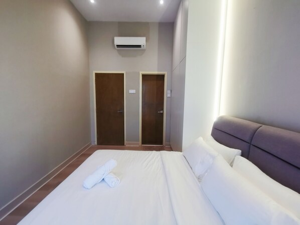 Una habitación de hotel con una cama, dos puertas y un equipo de aire acondicionado.