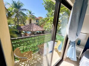 Un balcón con vista a una piscina, palmeras y un pabellón.