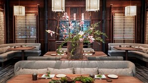 Un restaurant moderne avec une composition florale centrale, des tables en bois et des sièges rembourrés.