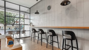 A modern bar area with wooden bar counter and black bar stools, large windows, and a view of the street outside. - 35.5 inn (Hengchun)
