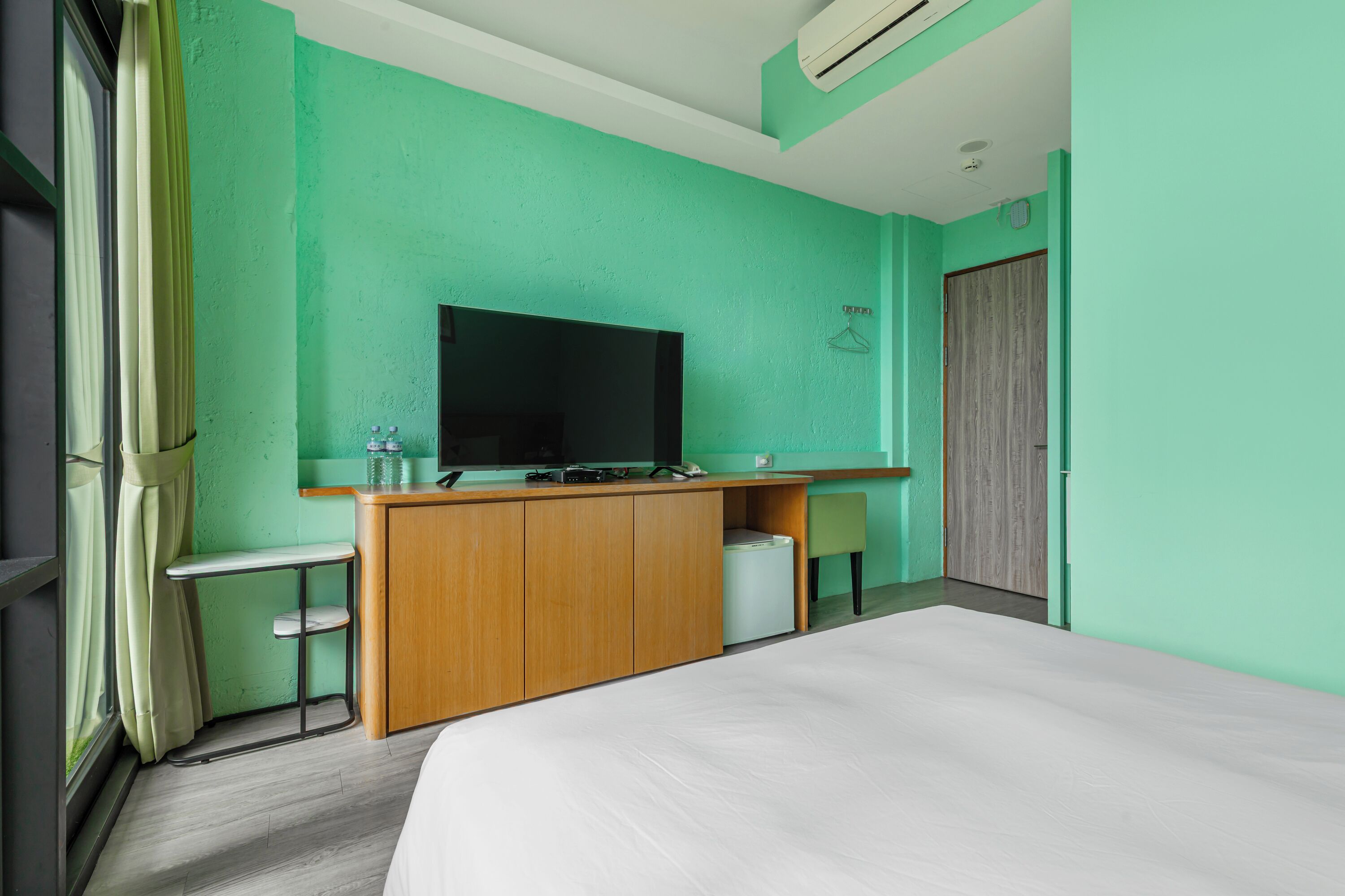 Une chambre d’hôtel équipée d’un lit, d’une télévision, d’un bureau en bois et d’un petit coin salon.