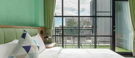 A hotel room with a bed, a nightstand, a lamp, and a view of the outside balcony.