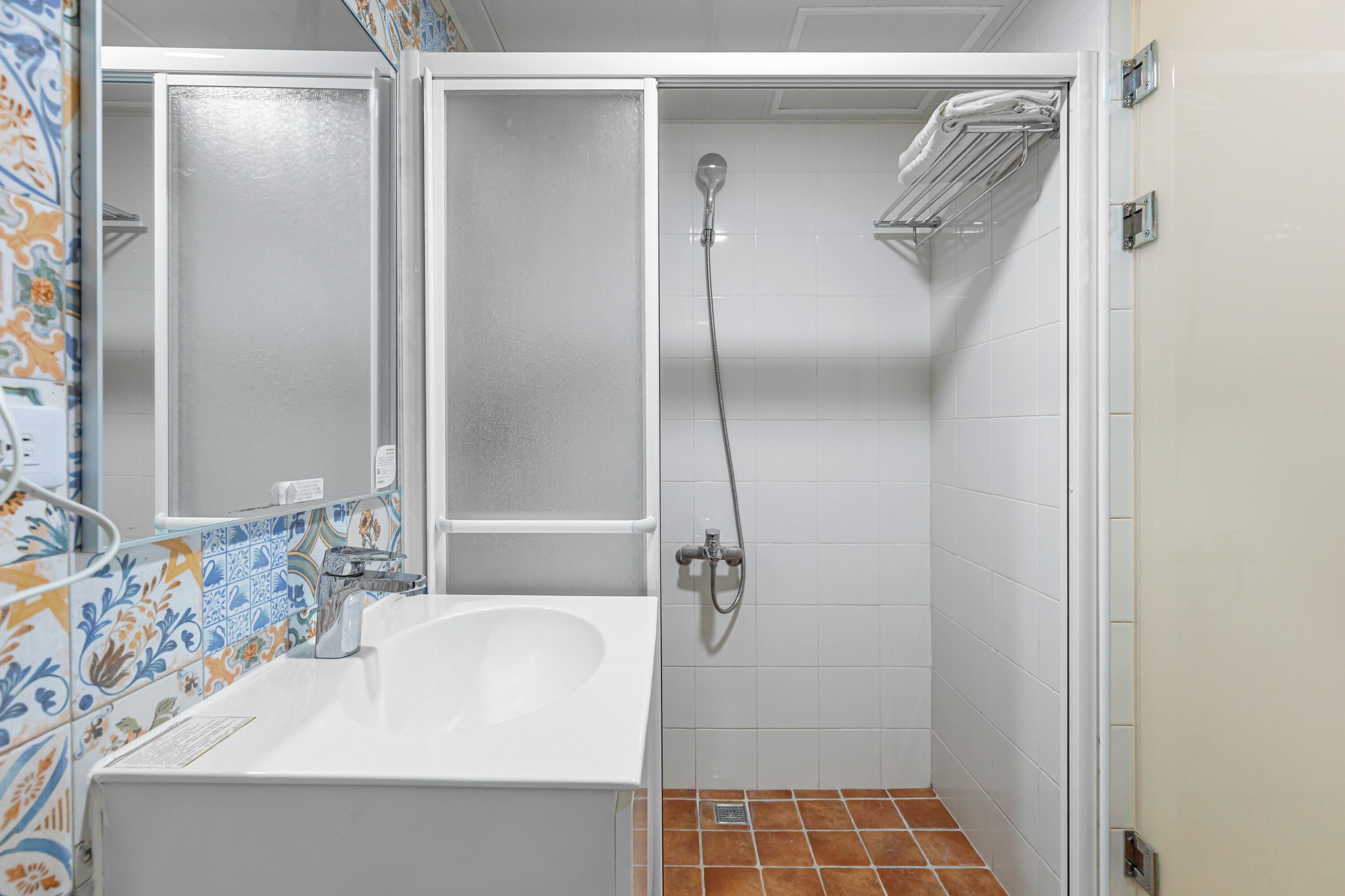 Une salle de bain avec une baignoire blanche, une douche équipée d’un pommeau de douche à main et un sol carrelé.