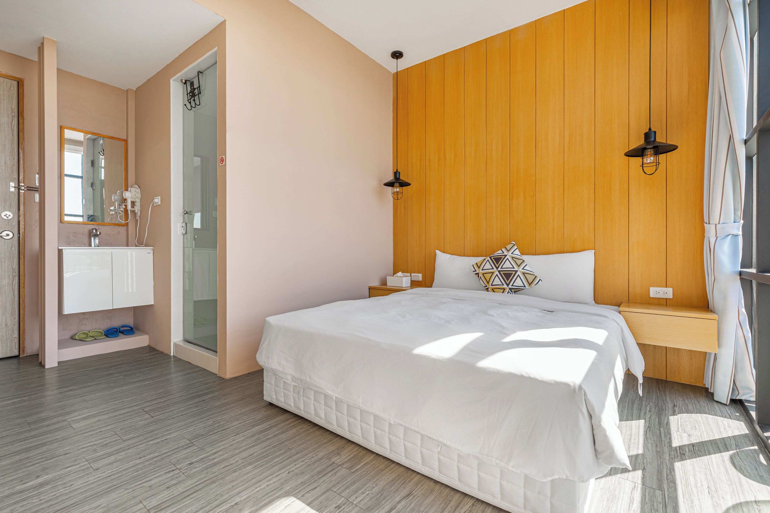A bedroom with a bed, bedside table, nightstand, and a wooden headboard.