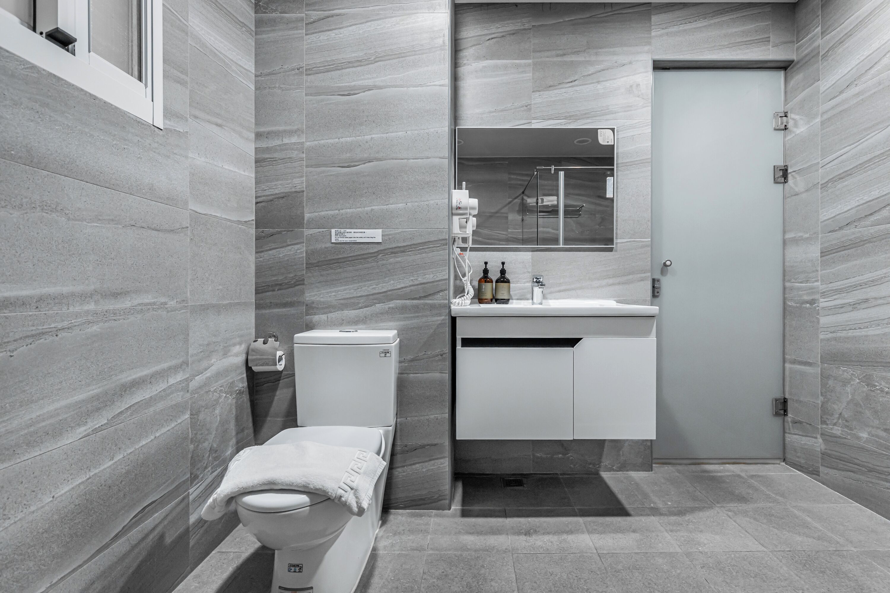 A modern bathroom with a toilet, sink, and mirror.