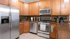 A modern kitchen with wooden cabinets, stainless steel appliances, and a tiled backsplash.