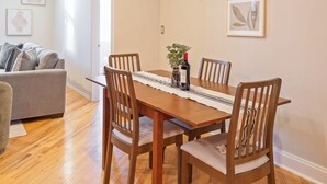 A dining area with a wooden table, four chairs, and a vase with flowers.