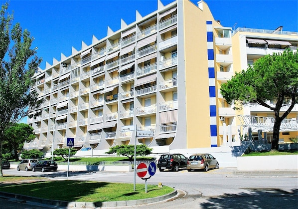 A multi-story hotel with balconies, a pedestrian crossing, and a no-entry sign.