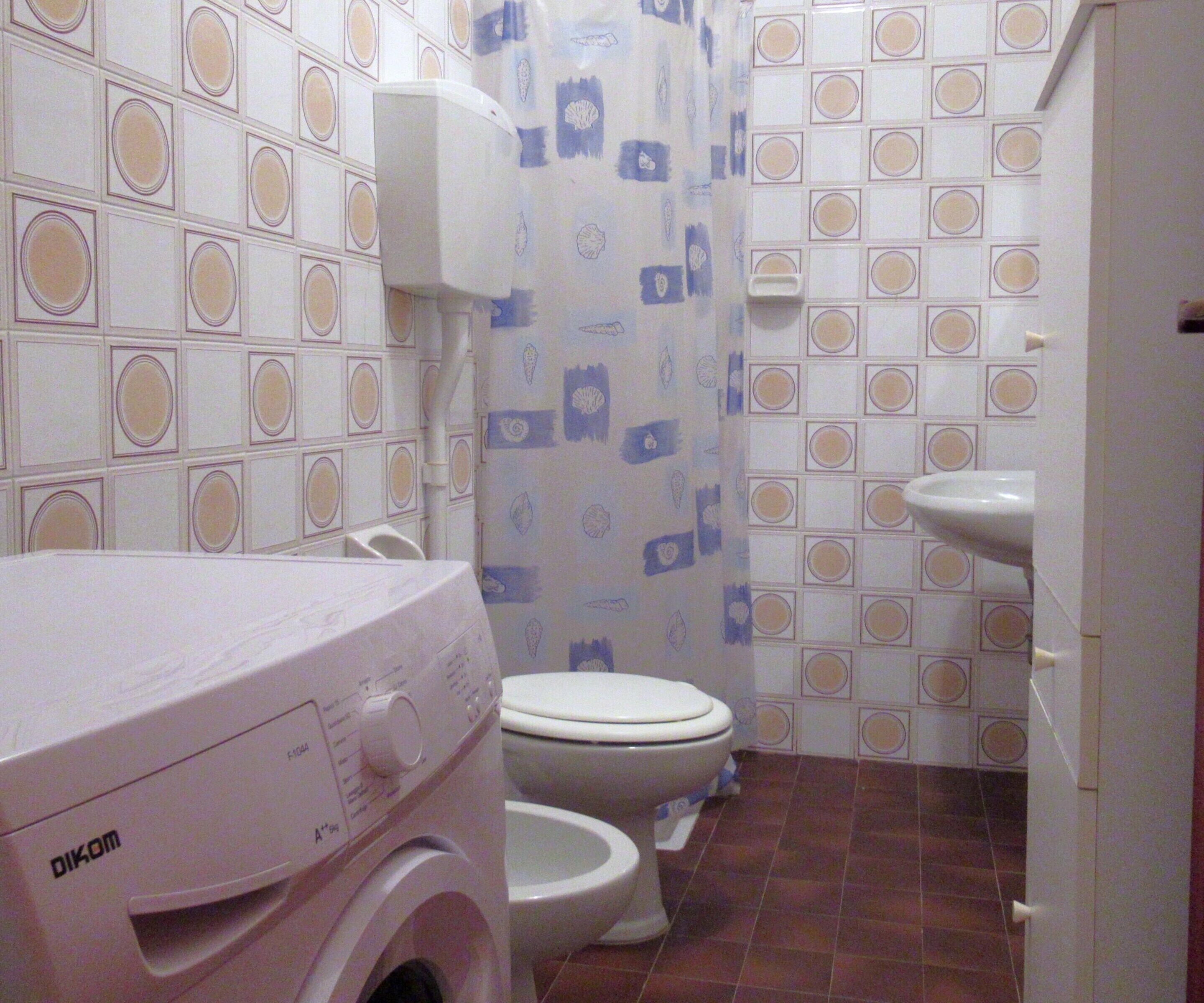 A small bathroom with a washing machine, a toilet, and a sink.