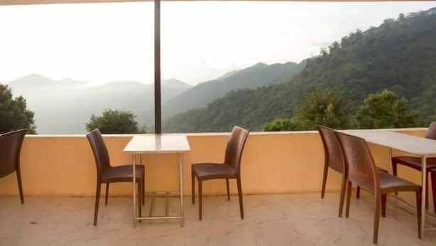 A balcony with a table and chairs, overlooking a mountainous landscape. - Namaste Resort (Bhedetar)