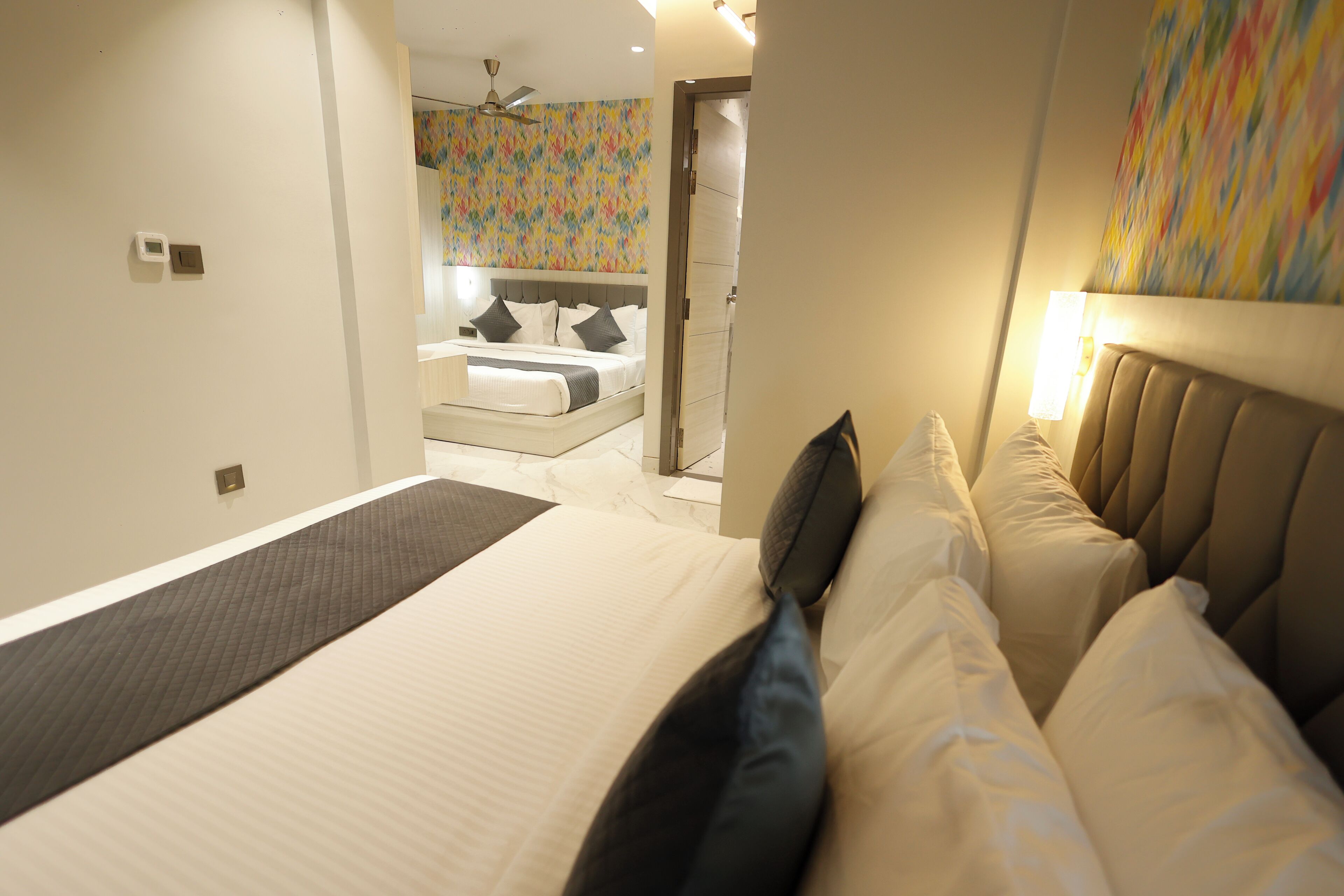 A modern hotel room with a large bed, a small sitting area, and a bathroom visible through an open door.