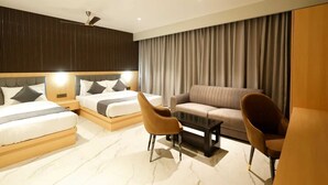 Ein modernes Hotelzimmer mit einem großen Bett, zwei Einzelbetten, einer Couch und zwei Sesseln.