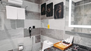 A modern bathroom with a marble sink, a toilet, and a shower. There are towels on a rack, a basket of toiletries, and a mirror with a light above it. - Pure Boutique Hotel  (Baku)
