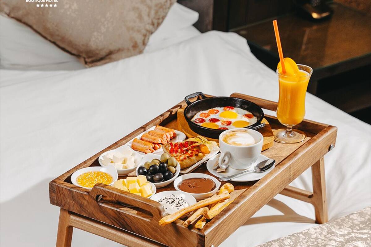 Una bandeja de madera con alimentos para el desayuno sobre la cama.