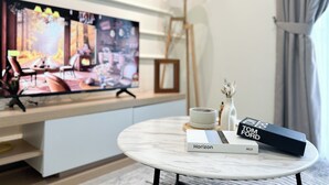 A modern living room with a flat-screen TV, a round marble coffee table, and a bookshelf. - Sunsuria Forum by Manhattan Group  (Shah Alam)