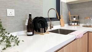A modern kitchen with a white countertop, a built-in sink, and a backsplash of grey tiles. - Sunsuria Forum by Manhattan Group  (Shah Alam)