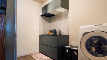A compact laundry room with a washing machine, a dryer, and a small countertop with a coffee maker.