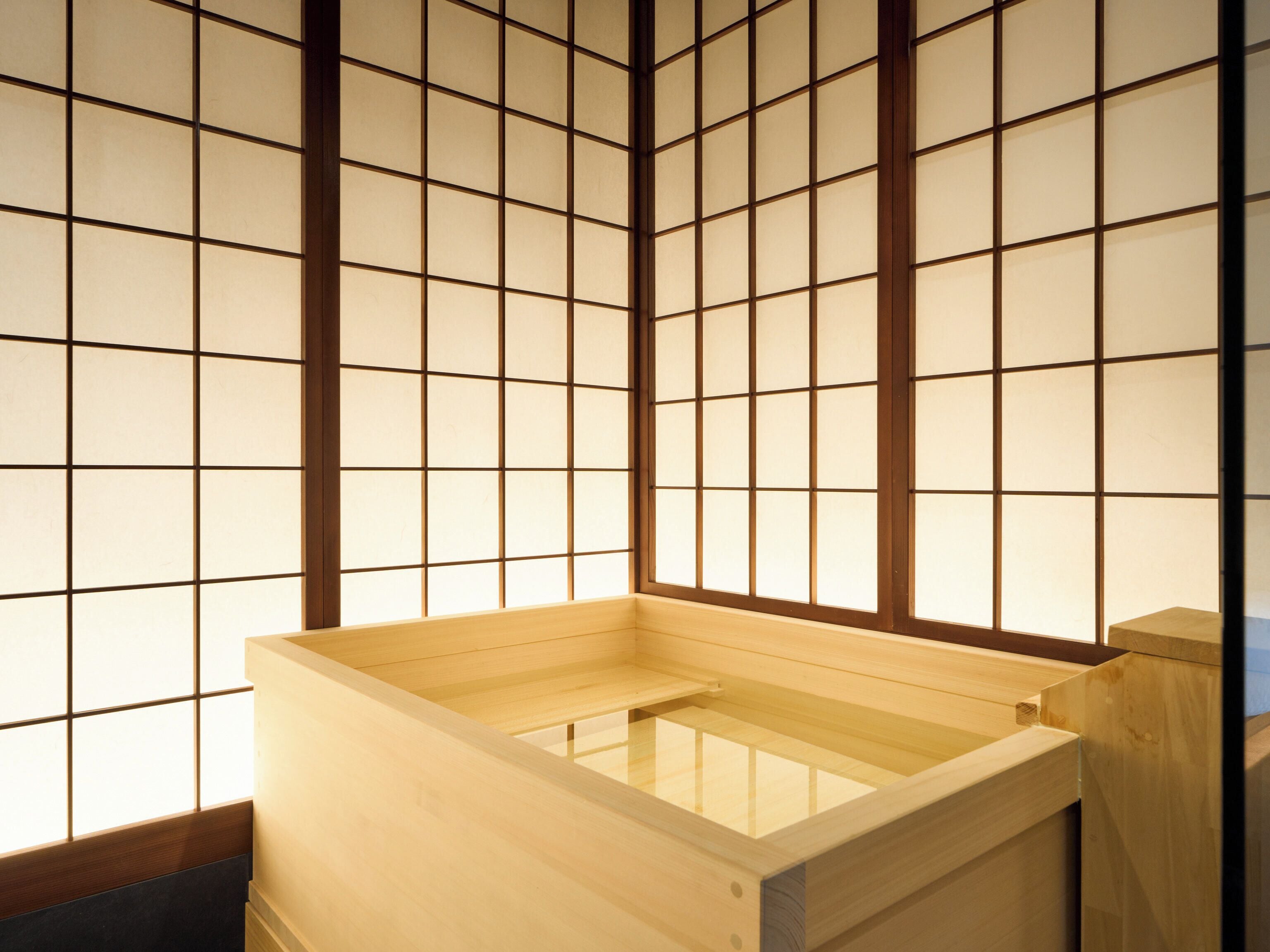 A traditional Japanese room with tatami flooring, a wooden washbasin, and shoji screens.