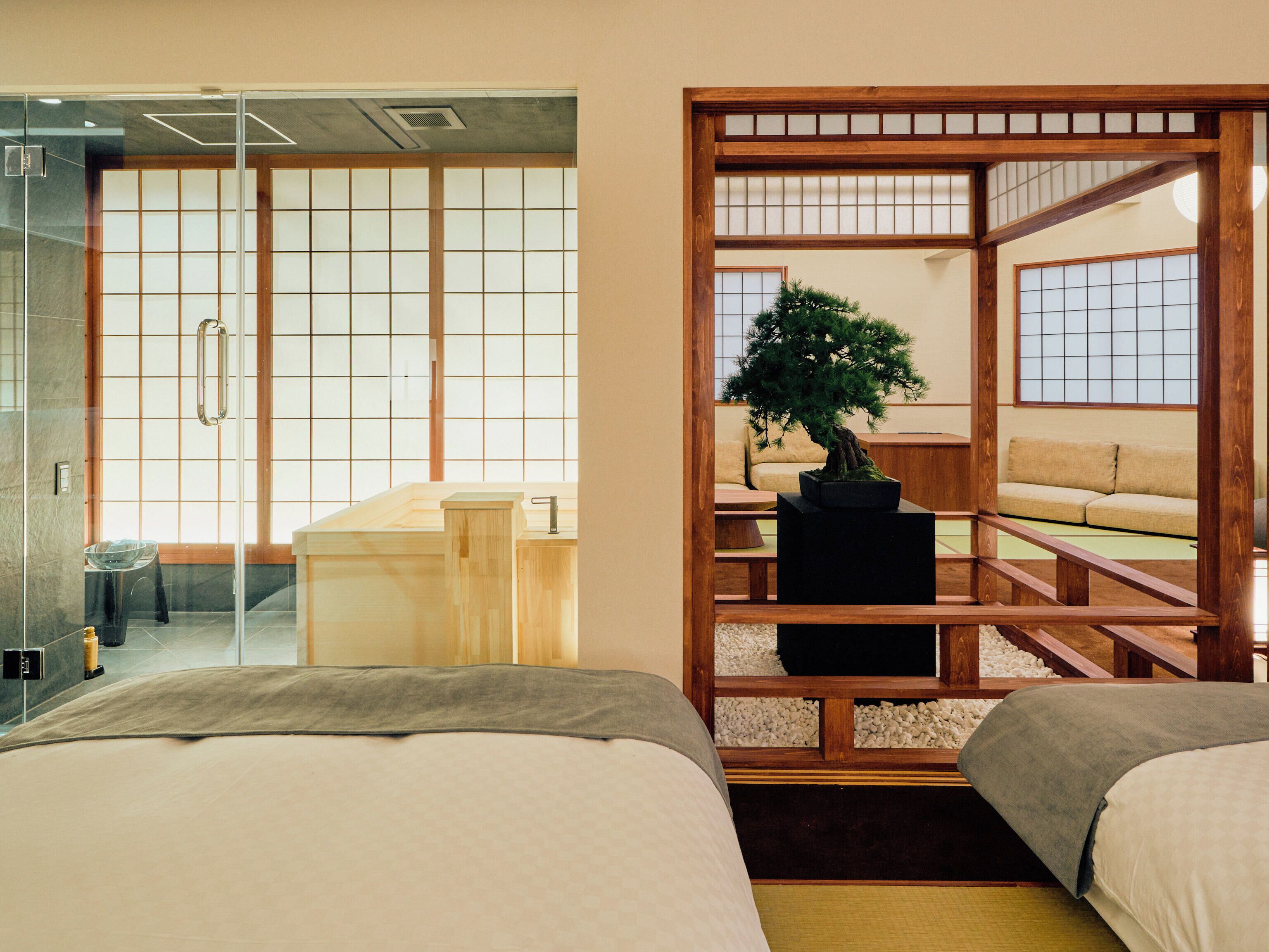 Une pièce de style japonais traditionnel, avec un sol recouvert de tatamis, un paravent en papier de riz (shoji), un bureau en bois, un bonsaï et un canapé.