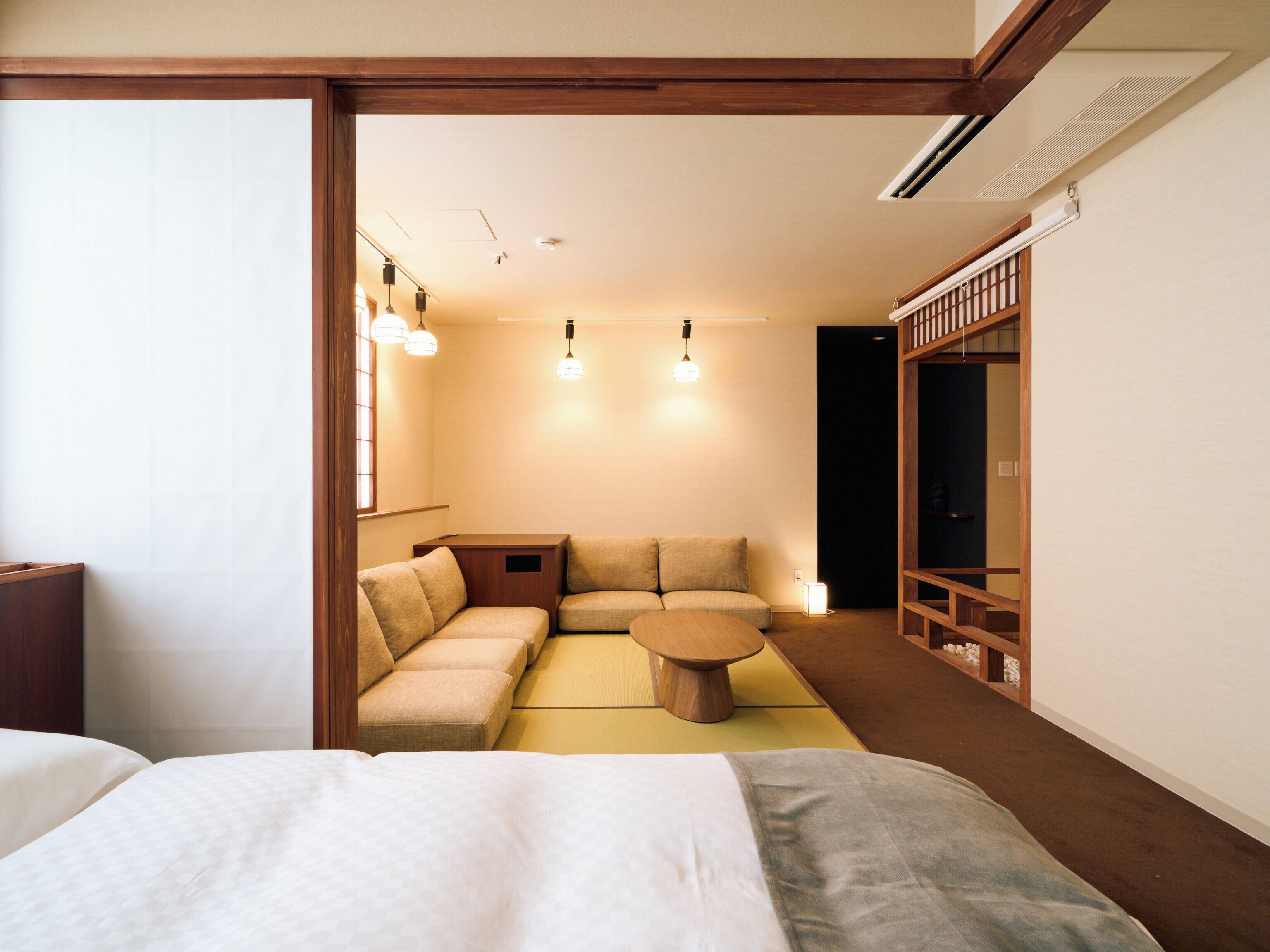 A hotel room with a bed, a sofa, a small table, and a cabinet.